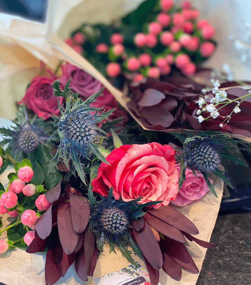 Elegant floral arrangement with pink roses, purple flowers and decorative elements